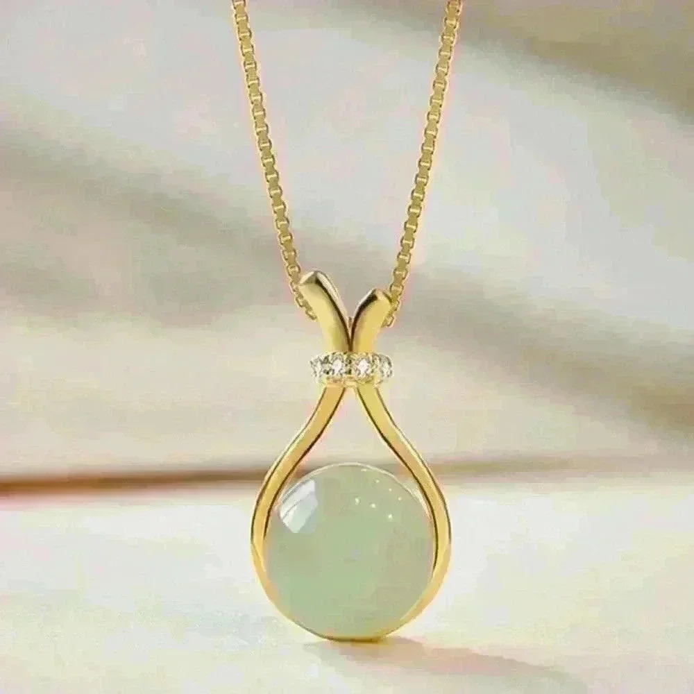 Jade Stone encased in a sleek gold necklace, accented with a sparkling c…